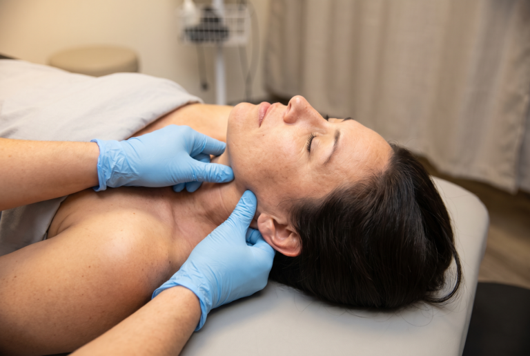 Physical therapist palpating a patient's jaw and neck muscles during a TMJ evaluation